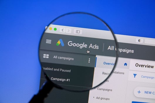 Google Ads interface under a magnifying glass, a key player among b2b advertising platforms for digital marketers.