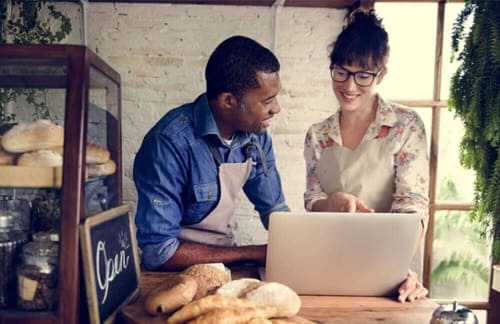 Two people in a bakery looking at a laptop.